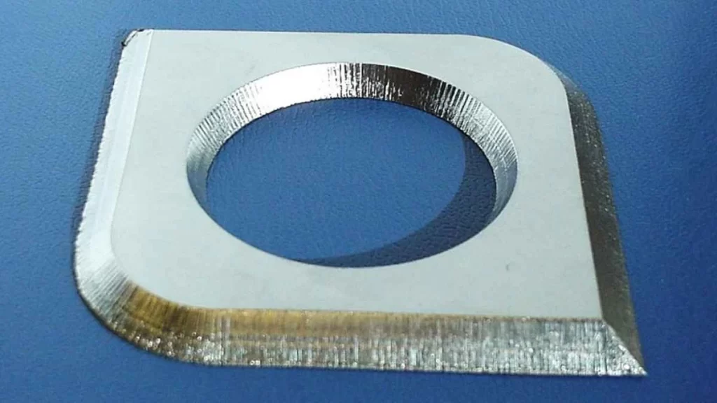 A Close-up of a metal part cut by laser, showing smooth edges and a central hole.