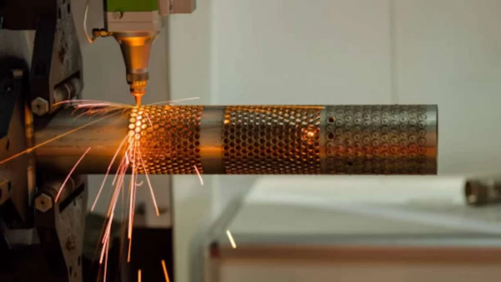 An image of laser cutting machining. It shows a high-powered laser precisely cutting through a metal rod with clean holes