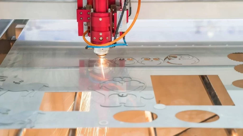 The image depicts a laser engraving machine in action. It uses a high-powered laser beam to shape precise, permanent designs into a material's surface.