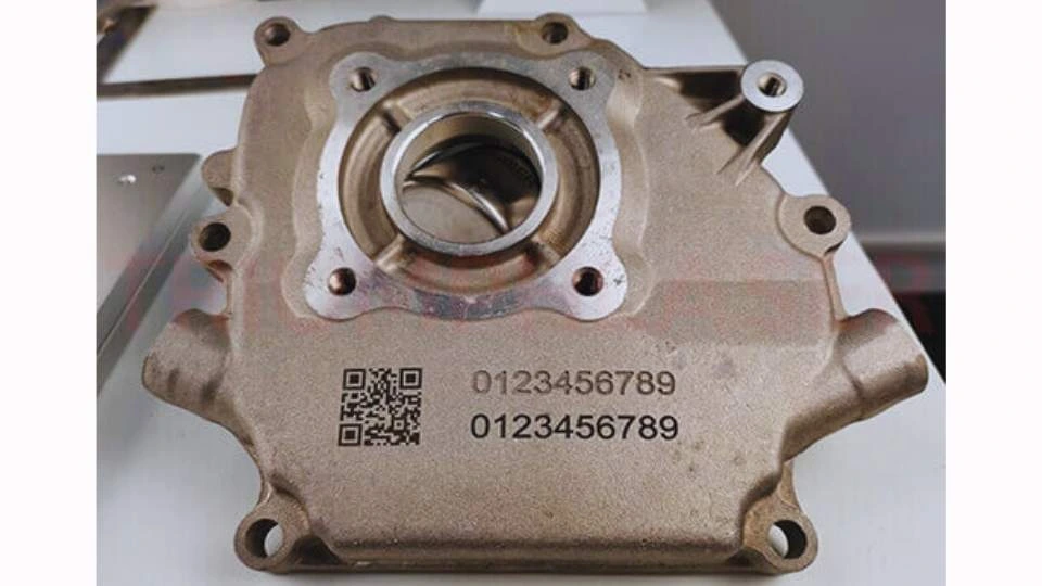 A close-up of a laser-marked motorbike engine part displaying a barcode and serial number.