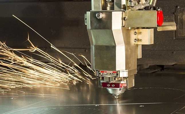 A cutting machine with its tip near the surface of a metal sheet and producing sparks