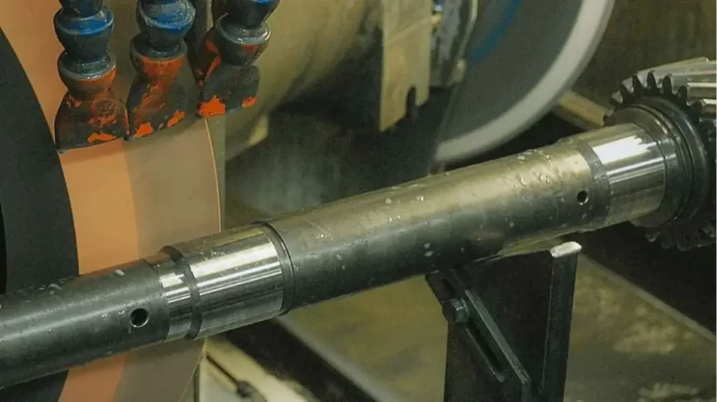 An image of OD grinding. It shows an automotive shaft component being externally ground for a smooth and shiny appearance