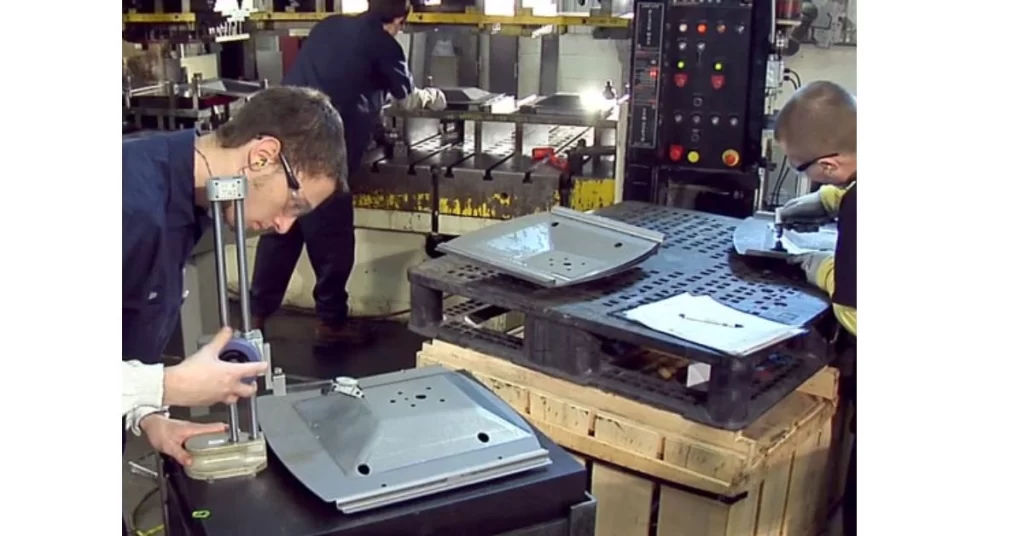 An image of stamping factory setup, two engineers inspecting stamped parts with probes