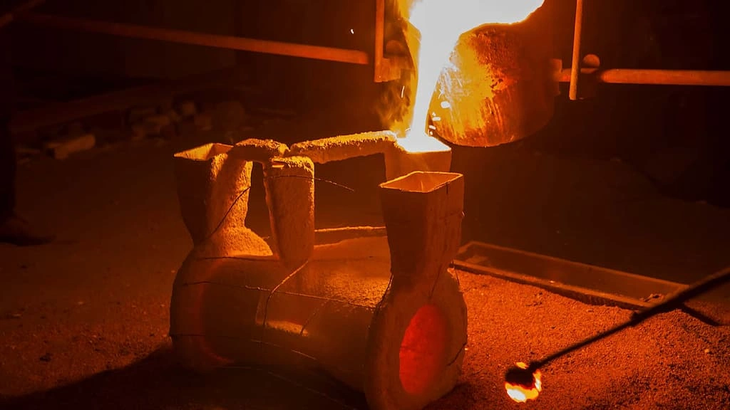 A close-up view of stainless steel investment casting, pouring hot molten stainless steel into the mold cavity