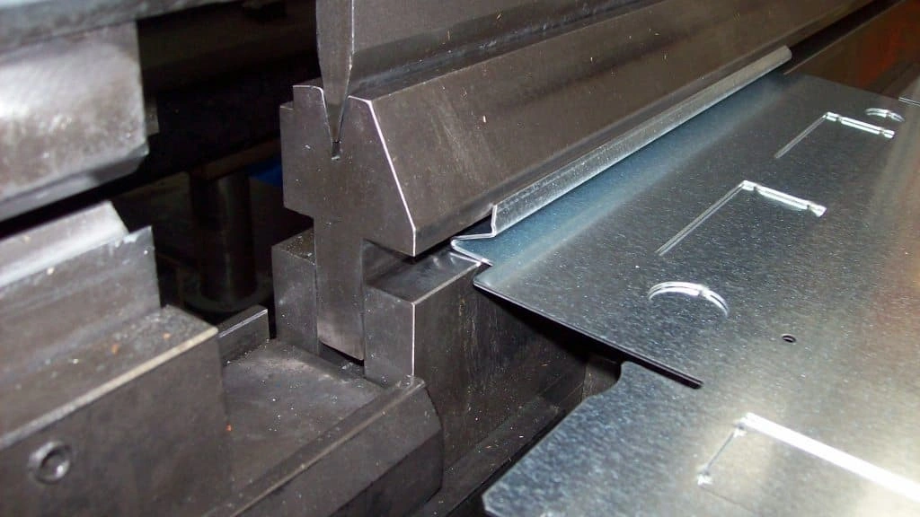 A closeup view of bending stainless sheet in a die and punch setup 