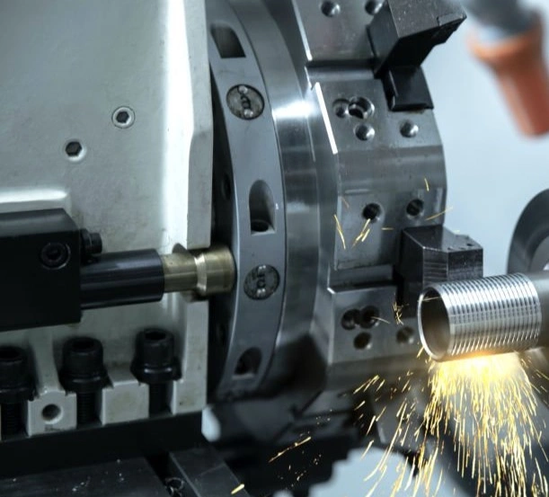 A CNC lathe machining threads on a metal tube with sparks forming