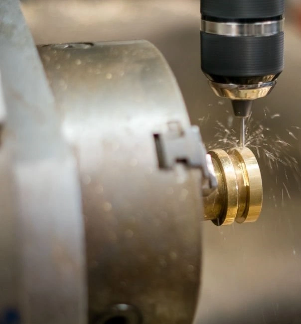 An image of a lathe machine drilling a hole across a metal part