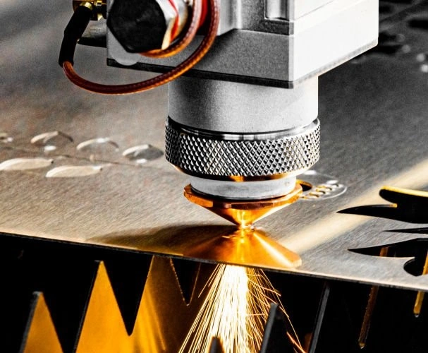 A nozzle with a knurled surface produces sparks as it cuts a metal sheet