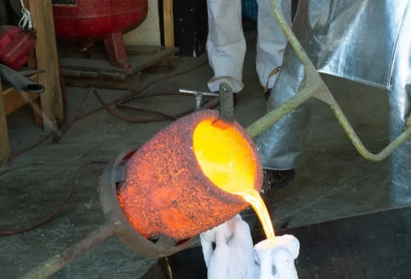 Molten metal being poured from a crucible during metal casting.