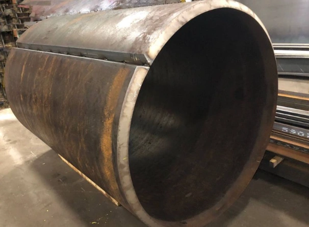 A thick metal plate rolled to form a tube showing beveled edges