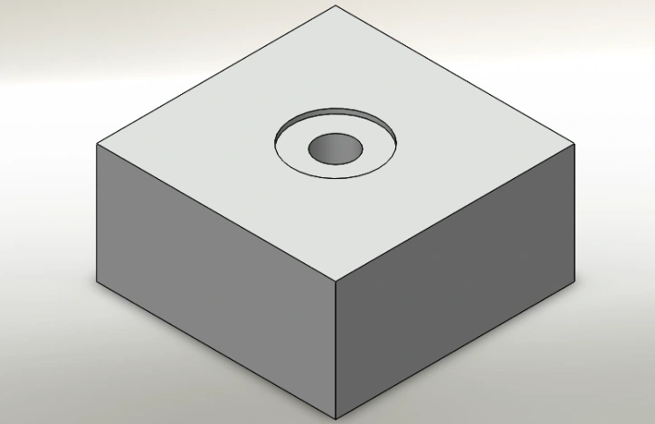 An image of a square block with a spotface hole on the upper surface