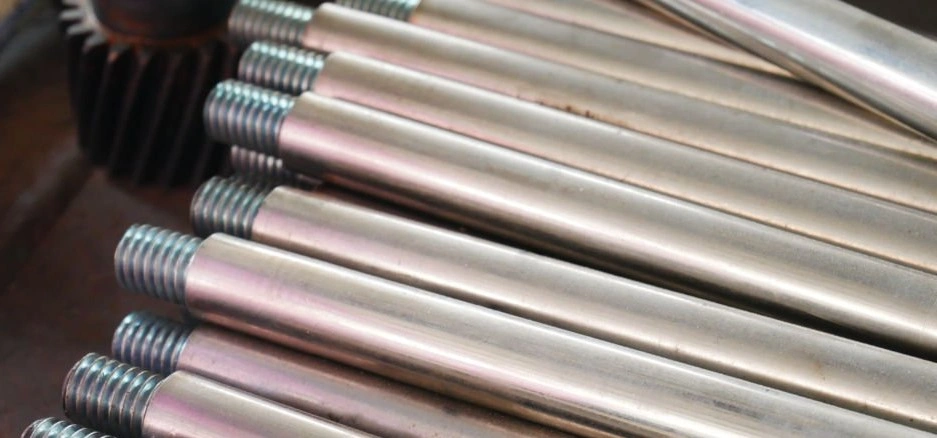 An image of several steel shafts with threads on one side arranged on a surface