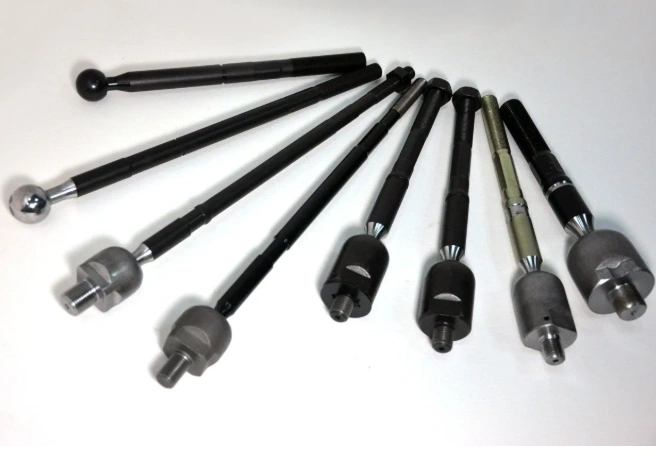 Eight machined metal parts of different sizes showing rack ends of a steering system