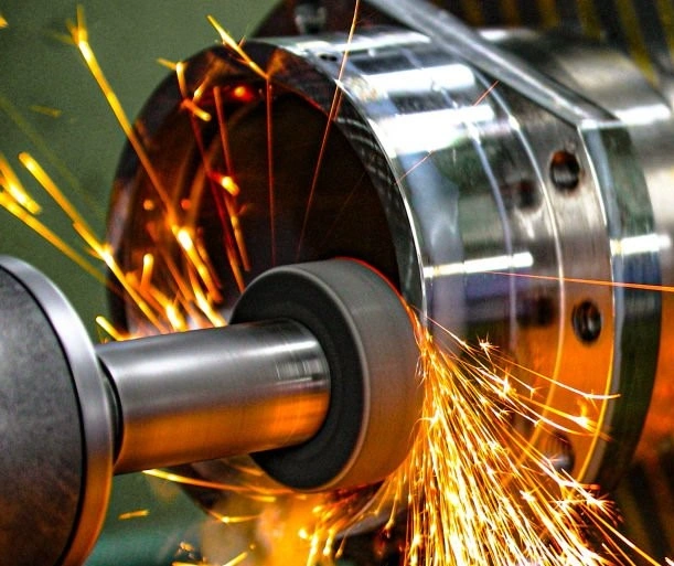 A close-up photo of a cylindrical grinding process, with sparks flying