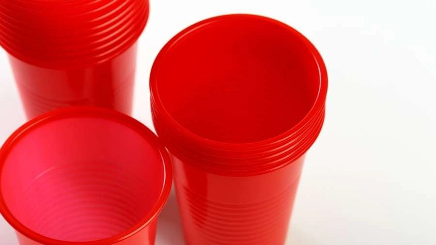 An image of HDPE disposable cups neatly stacked. It showcases their smooth red colour and lightweight features