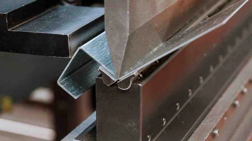 An image of the sheet metal forming process. It showcases the deformation of a metal sheet into a specific shape using force and dies