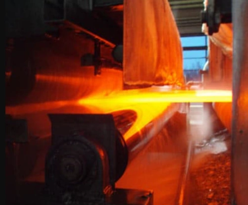 An image of a red hot piece of metal being passed through rollers in a heat treatment process