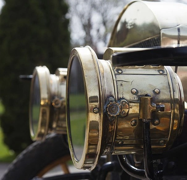 A closeup image of bright brass headlights of a vintage car