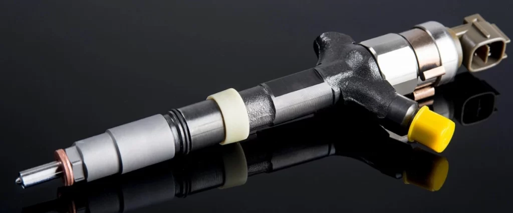 An image of a common rail fuel injector against a reflective black surface