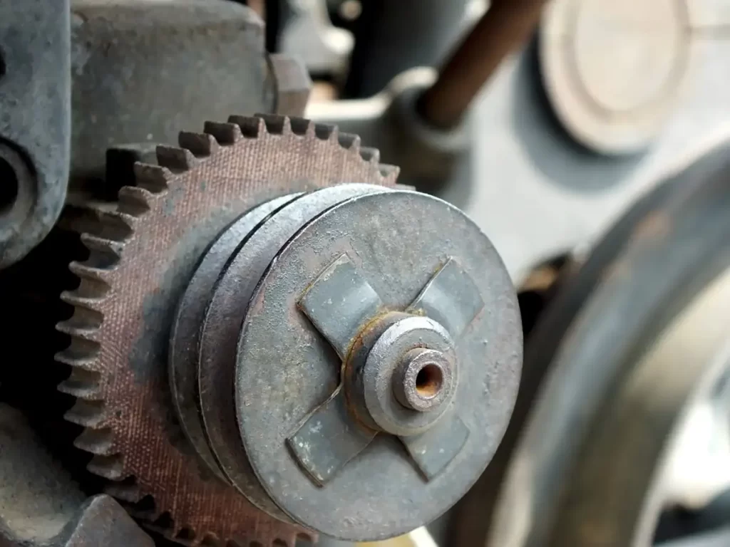 A spur gear alongside a pulley for a mechanism for an older generation car