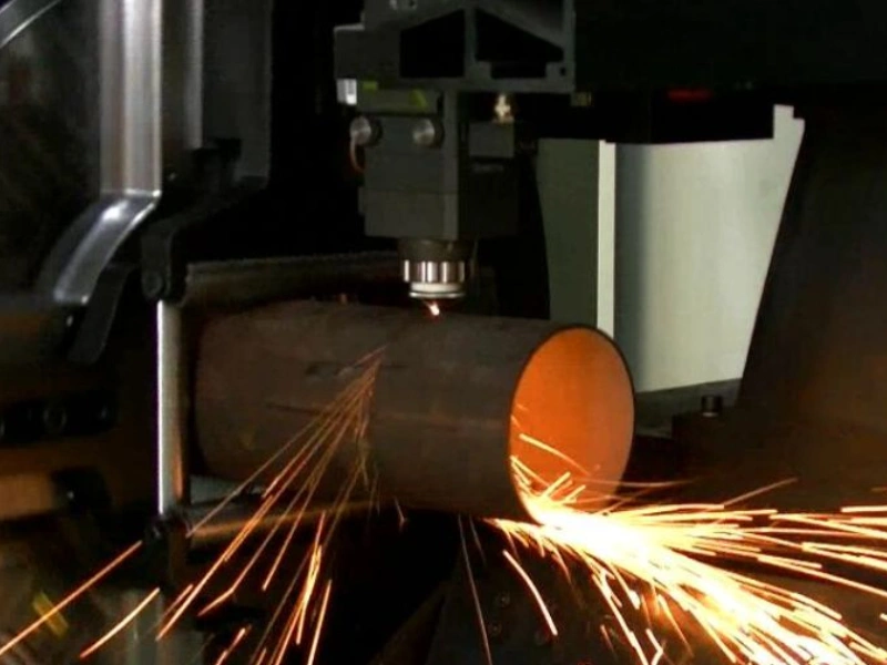 A picture of the laser cutting process for a metal pipe with sparks forming