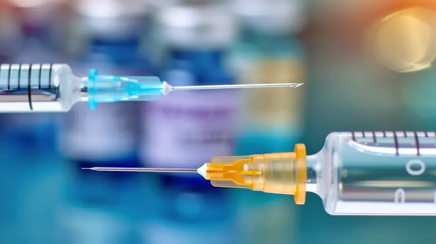 An image of two medical syringes and sharp needles with yellow and blue caps