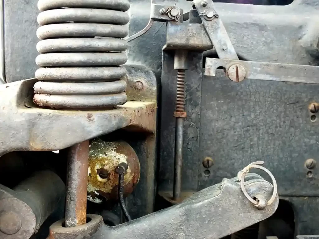 A closeup image of an old vehicle suspension system with a large coil spring