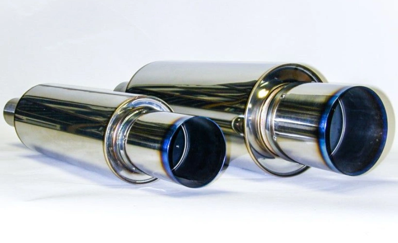 Two titanium mufflers with a polished finish and blue heat discoloration near the exhaust tips, on a white background