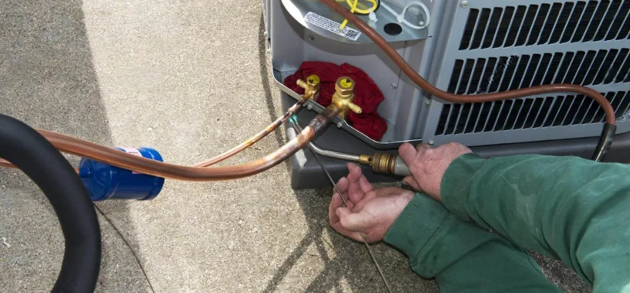Man holding electrode and TIG torch performing weld on a copper brass pipe