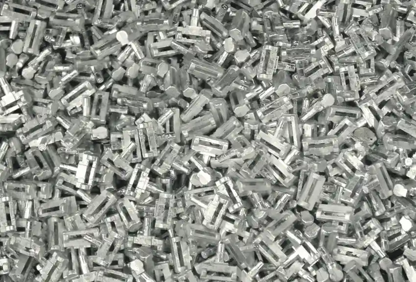 Close-up of numerous small, silver zinc die-cast parts piled together.