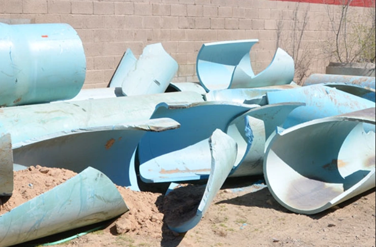 Fragments of blue plastic pipes after brittle failure 