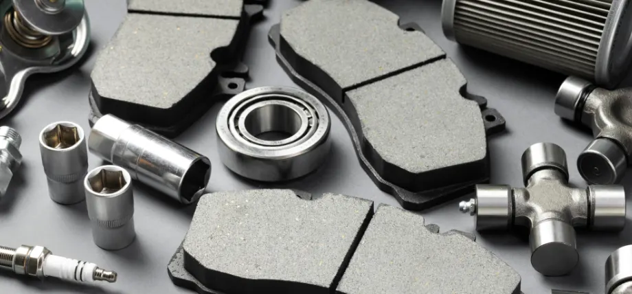 Spark plus, brake pads, lugs and other tools on a gray background