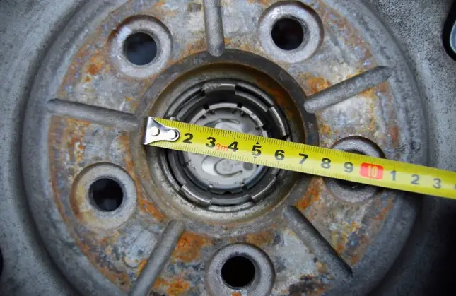 An image of a car wheel center bore with a measuring tape