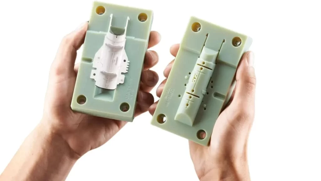 The image shows a close-up of a small plastic part being formed in a compact soft tooling mold.