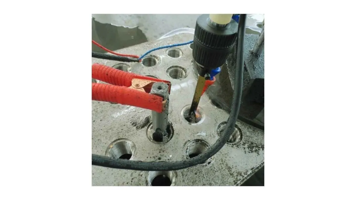 An image showing the EDM machine in operation to remove a broken tap from a workpiece. 