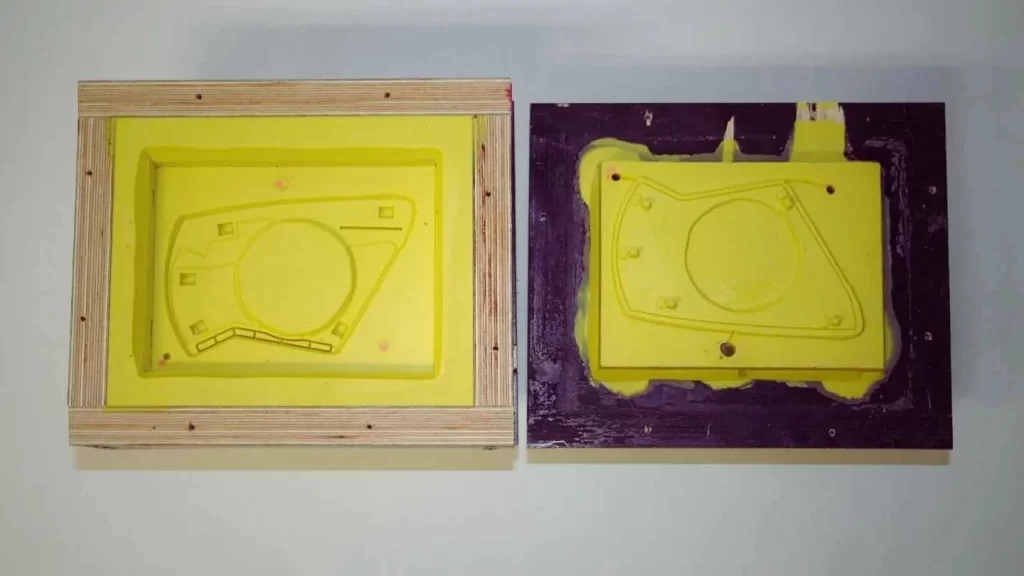 The image shows a yellow-colored part being ejected from a die, with the actual part design imprinted in the mold.