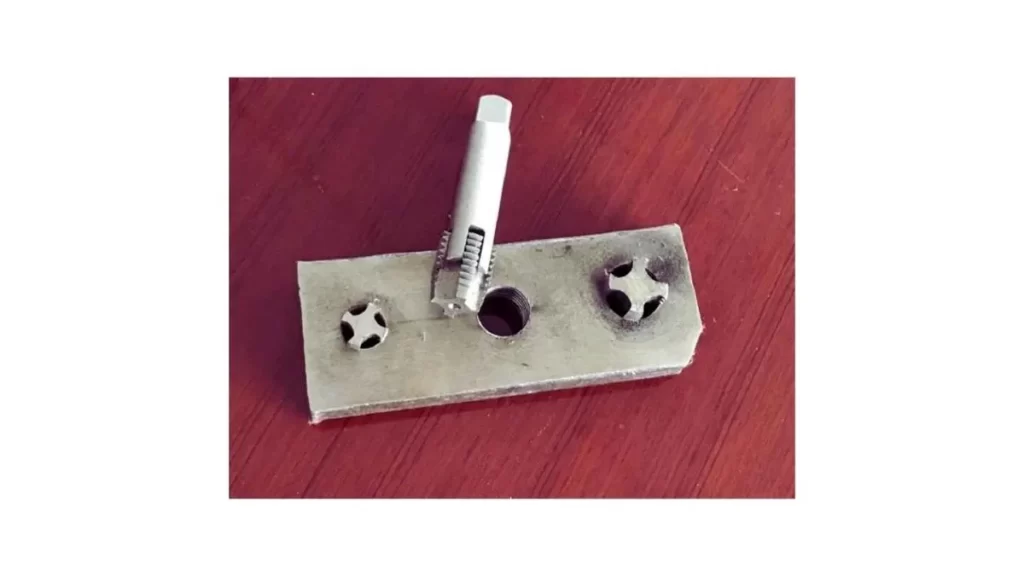 An image showing a punch being used to remove a broken tap from a workpiece. 