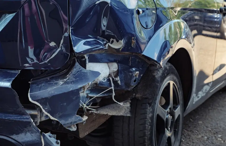 An image of an extensively damaged navy blue car rear bumper 