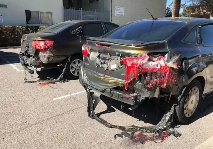 Two cars in a sunlit parking lot with rear plastic parts melting