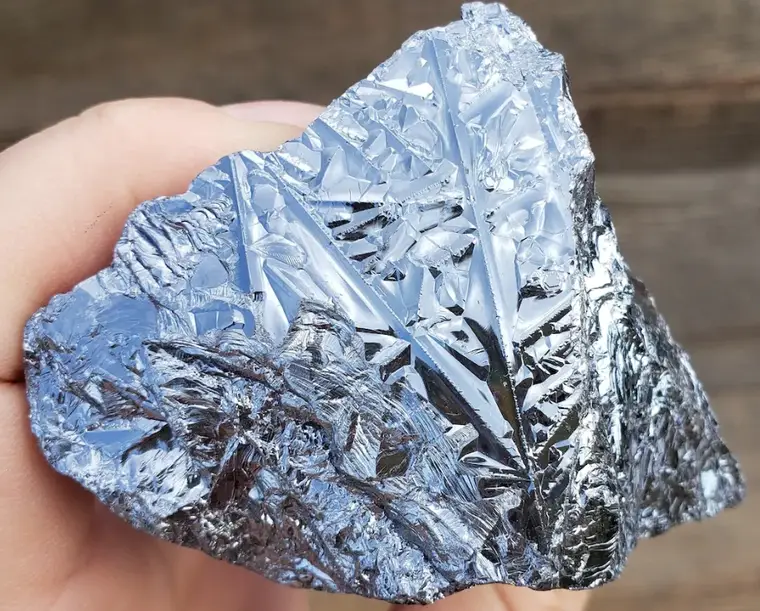 A fragment of shiny silver silica held in a hand