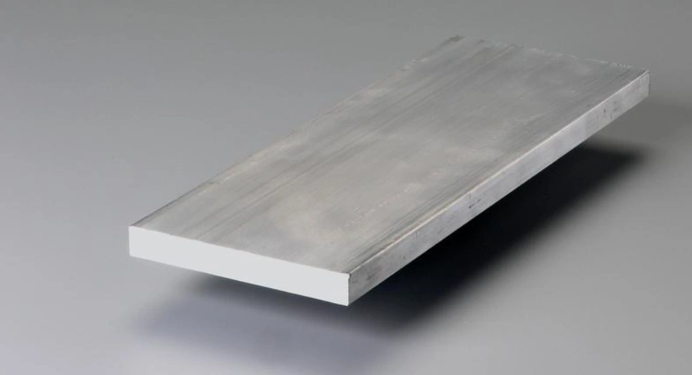 A 6061 aluminum plate on a grey surface with a shadow beneath it
