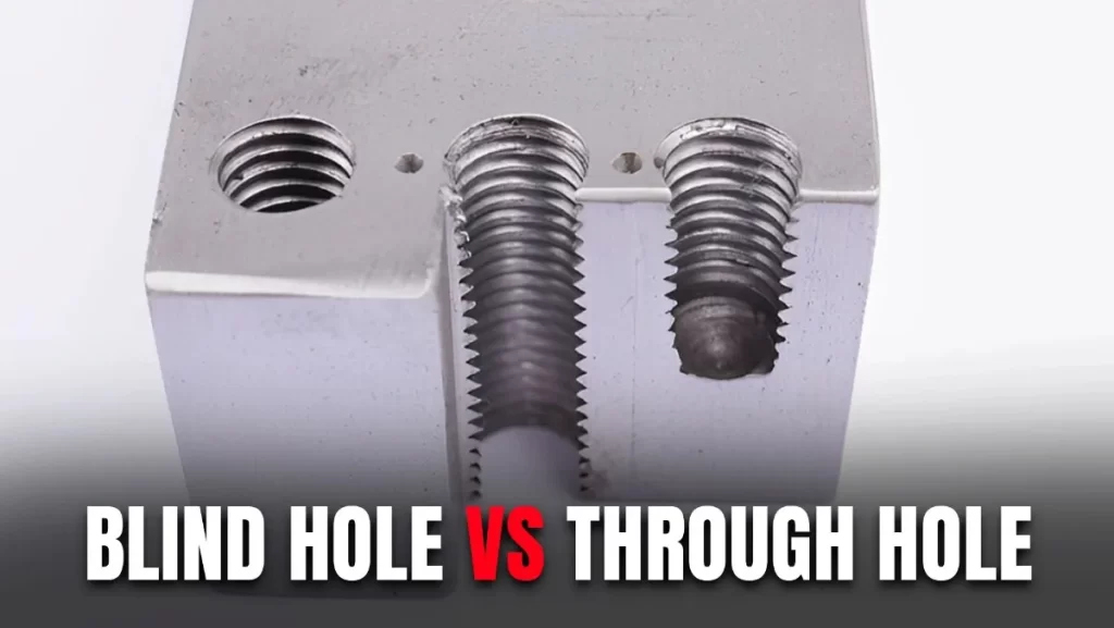 A close-up of a metal block with three holes, two threaded (one blind, one through) and one plain.