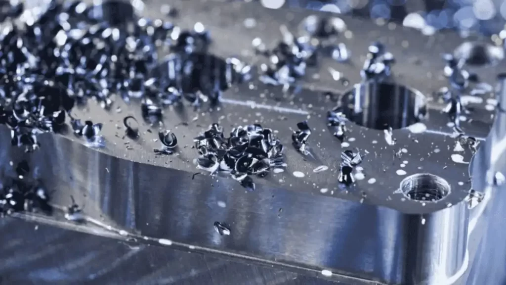 Machined part with metal chips visible on the surface.