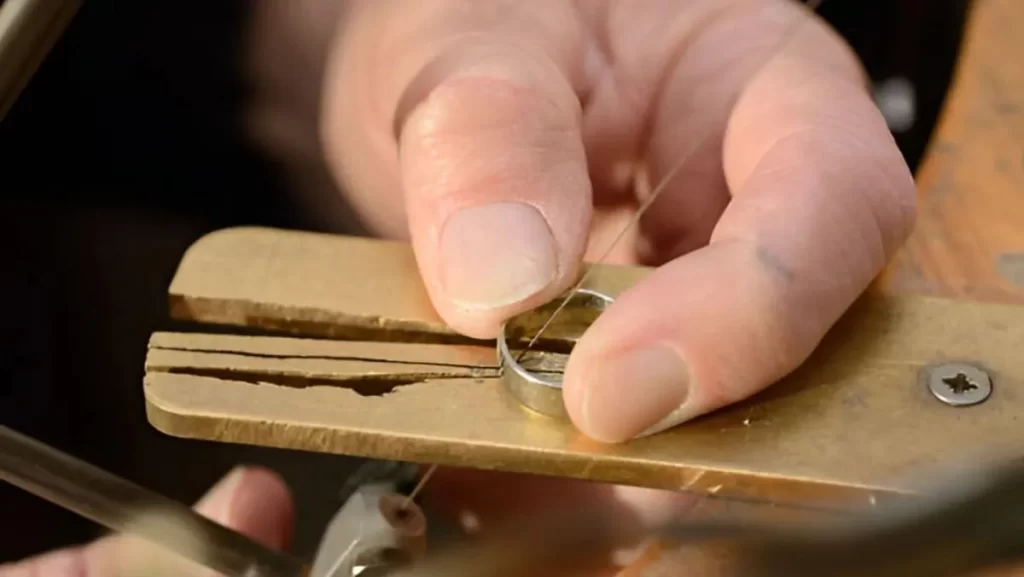 A close-up of a person's hands holding a small, round metal piece 