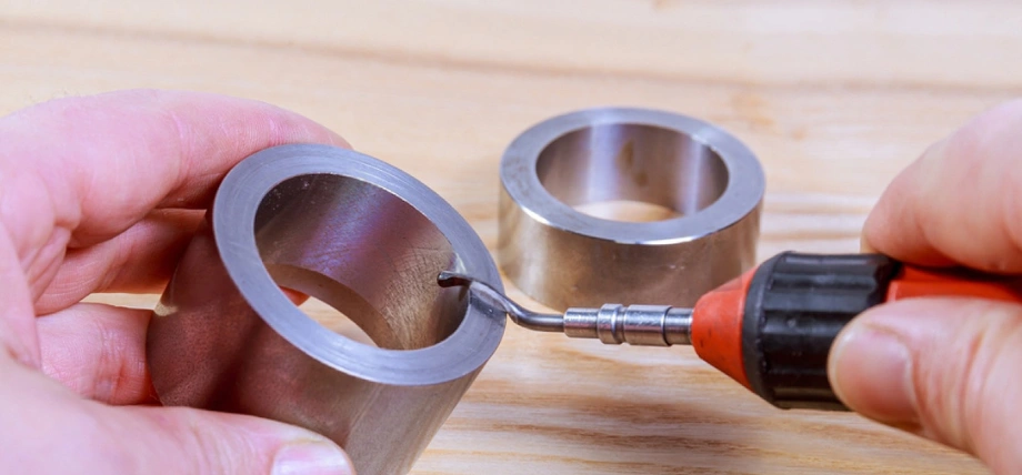 Two metal cylinders with a deburring file scratching the surface to remove burrs