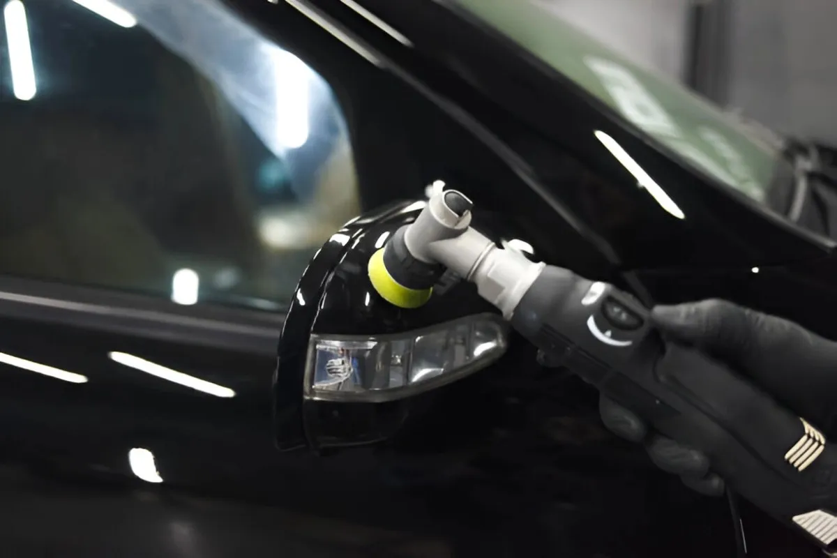 A car light housing being polished to a bright reflective finish on a polishing wheel