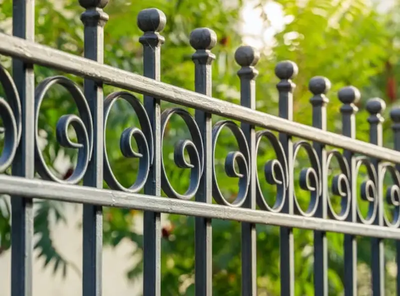 A black wrought iron fence with curly decorative features 