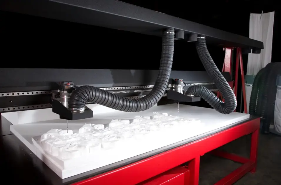 A CNC router cutting through a white block of styrene material