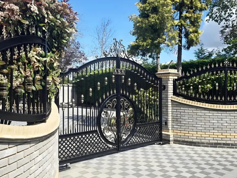 A wrought iron gate and a section of a brick wall 