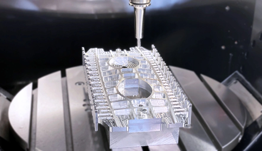 An aluminum part with complex geometries and two circular recessions on the rotating table of a vertical milling center